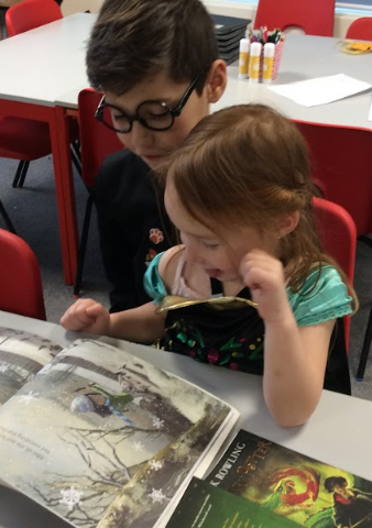 Two students in costumes, reading a book together