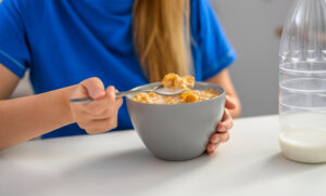 Girl eating cornflakes with oat milk, healthy food breakfast cereal